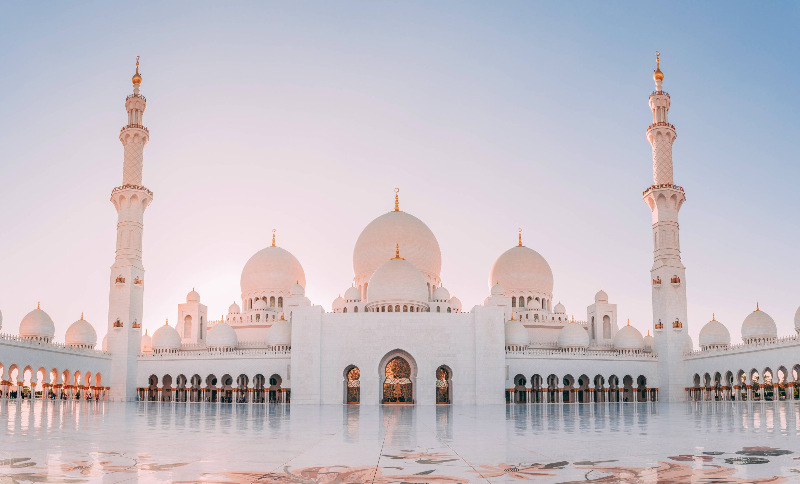 Vue frontale de la Grande Mosquée Sheikh Zayed à Abu Dhabi baignée de lumière dorée.