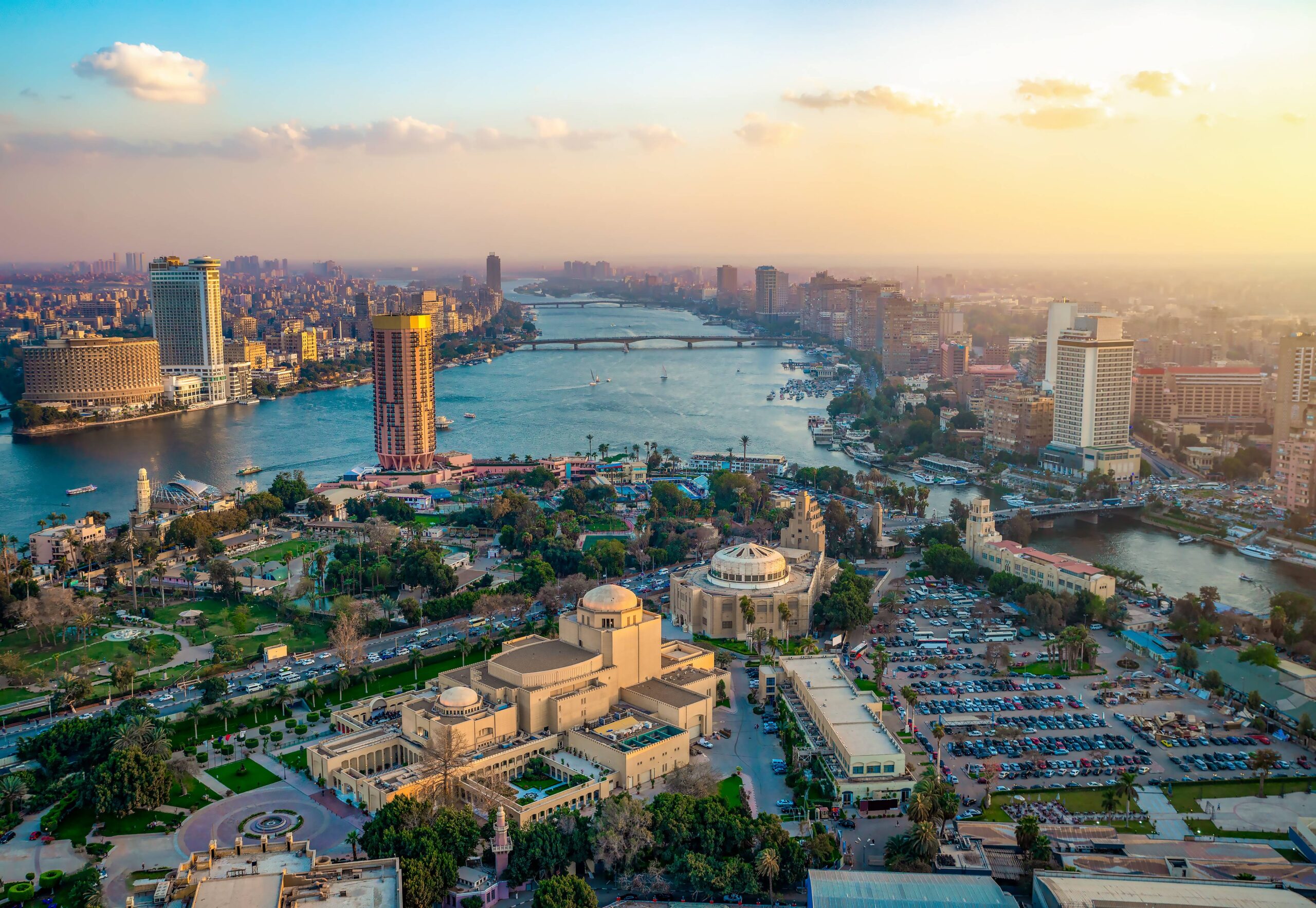 Panorama urbain du Caire au coucher du soleil, avec la silhouette des monuments emblématiques et du Nil.